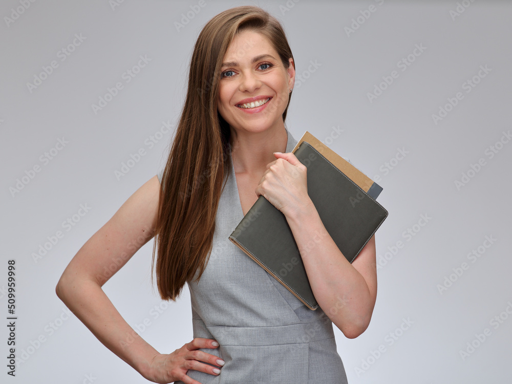 Smiling teacher woman or student standing with one hand oh hip and holding books on isolated gray background. Smiling teacher woman or student standing with one hand oh hip and holding books on isolated gray background.