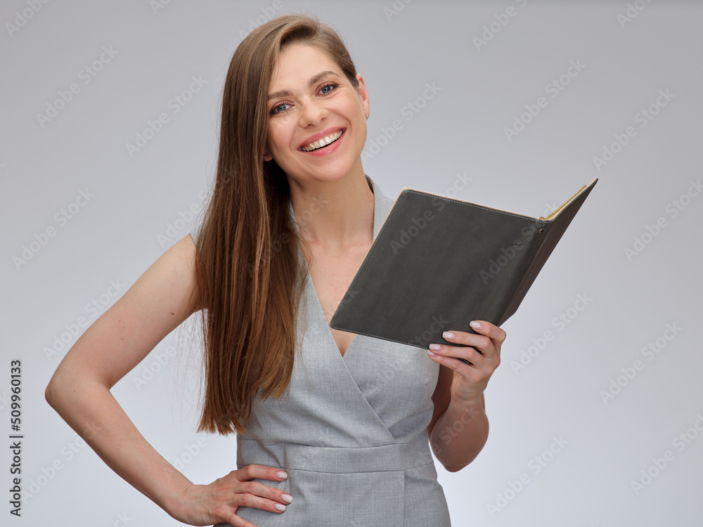Smiling teacher or business woman, student standing with open book and holding one hand on hip. isolated portrait on gray. Smiling teacher or business woman, student standing with open book and holding one hand on hip. isolated portrait on gray.