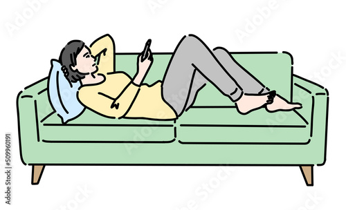 ソファーの上で寝転がってスマホを見ている女性
