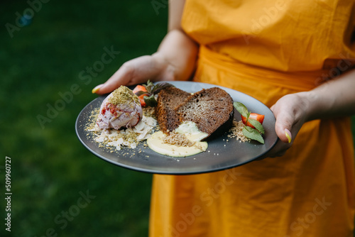 Closeup of a woman holding a plate with traditional Moldavian dessert baba neagra. photo