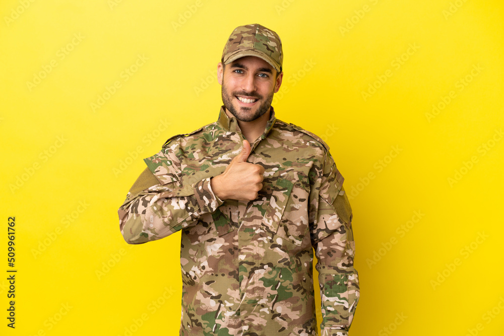 Military man isolated on yellow background giving a thumbs up gesture Military man isolated on yellow background giving a thumbs up gesture
