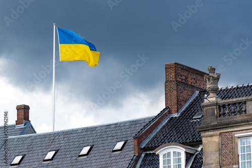 Ukrainian flag waiving on the roofs of the city with threatening grey clouds on background