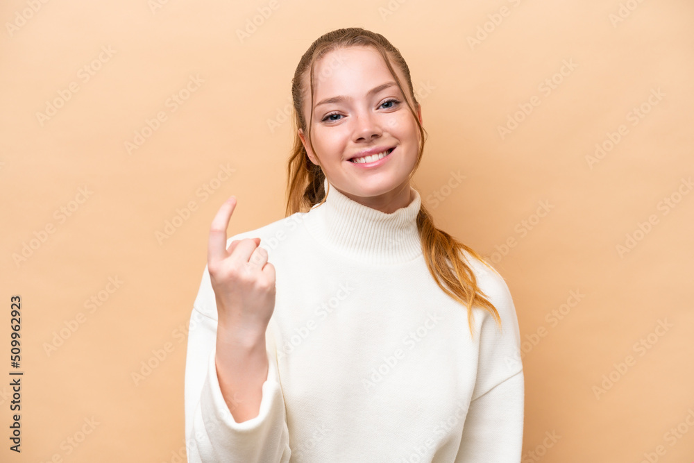 Fototapeta premium Young caucasian woman isolated on beige background doing coming gesture