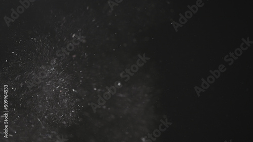 Dust particles float in neutral light on black background