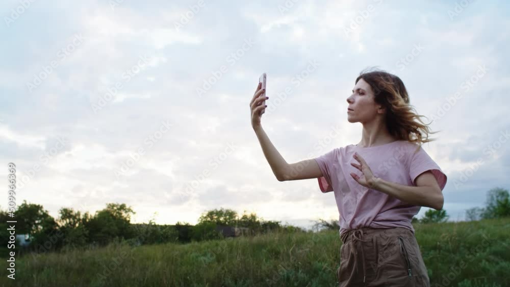 a young woman is happy to communicate in video communication through a phone on the mountain hills during sunset, for relaxation after a hike. rest of one person in nature, in the mountains. a young woman is happy to communicate in video communication through a phone on the mountain hills during sunset, for relaxation after a hike. rest of one person in nature, in the mountains.
