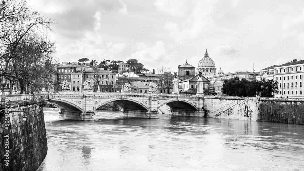 Black and white view of the bridge of Ponte Vittorio Emanuele II and saint Peter basilica over the Tiber river in Rome, Italy, Europe.