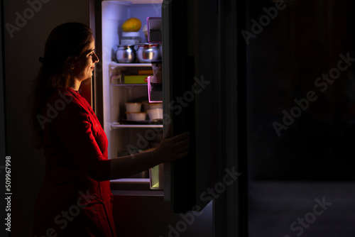 Young woman looking inside the refrigirator in kitchen photo
