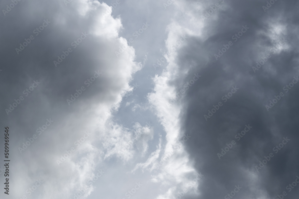 Two grey clouds passing each other with gap in middle, bright edge and dark center of cloud Two grey clouds passing each other with gap in middle, bright edge and dark center of cloud