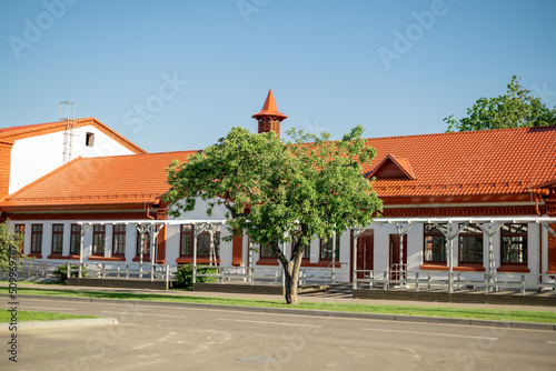 One-storey building with red-tiled roof and green tree in front of entrance