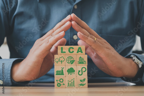 Hand arranging wood block stacking with icon ISO LCA standard aims for limited climate changing. LCA, Life cycle assessment concept.