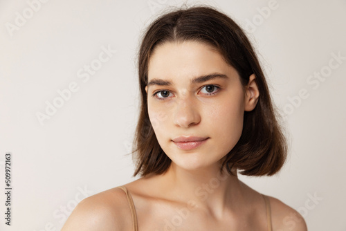 Close-up portrait of young eautiful woman posing isolated over grey studio background. Natural no makeup look