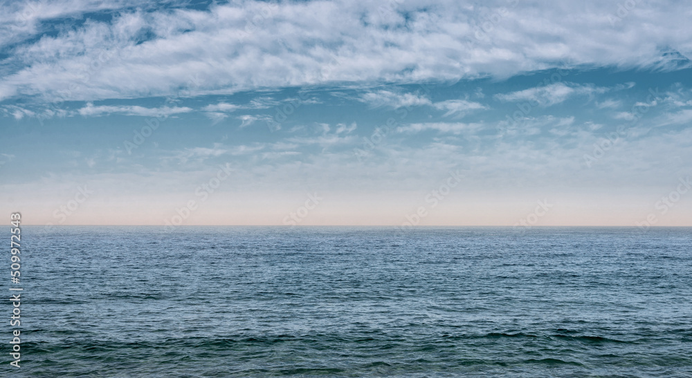 Fototapeta premium The surface of the sea under a cloudy blue sky. Blue wave surface of the sea going to the horizon.