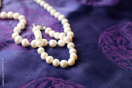 Luxury pearl necklace and bracelet on a purple background.