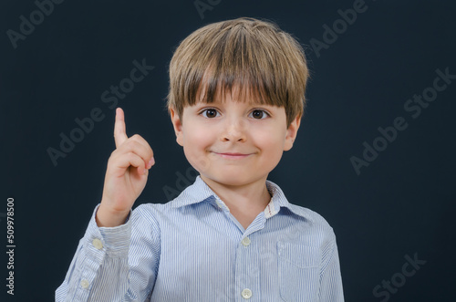 Portrait of a smiling little boy with finger up