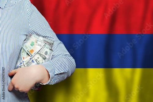 Currency exchange, banking and business in Armenia. Hand holds American dollars money against Armenian flag background.