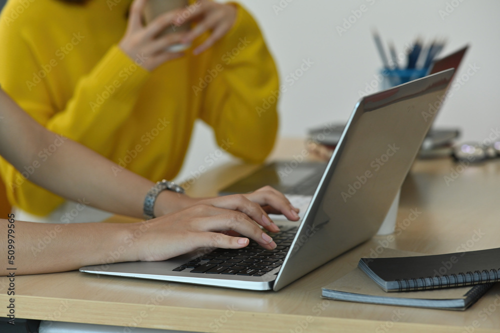The close up of Asian business female finger typing to reply e-mail between company and customer with her helpful colleague. Business and financial concepts.