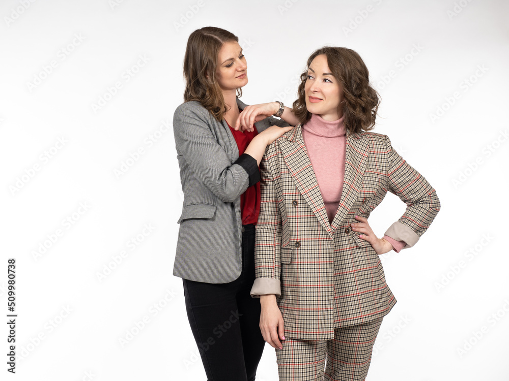 Two woman friends. Attractive woman on light background. Girls in business clothes. Adult woman stand nearby. Models pose and look at each other. Female of different height. Businesswoman friends Two woman friends. Attractive woman on light background. Girls in business clothes. Adult woman stand nearby. Models pose and look at each other. Female of different height. Businesswoman friends
