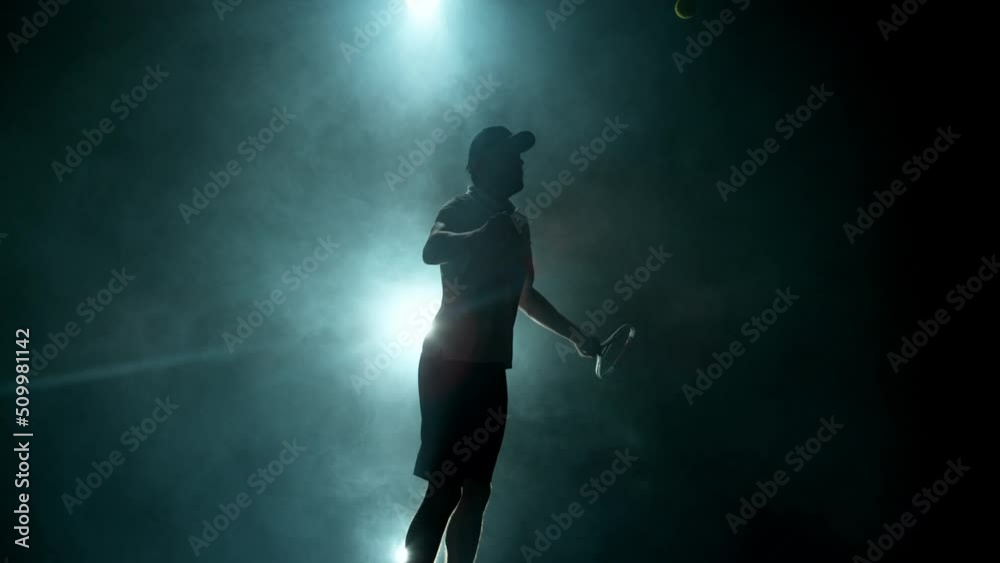 Super slow motion of tennis player silhouette hitting ball. Smoke effect around, black background. Filmed on high speed cinema camera, 1000fps.