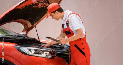 Car mechanic is using a tablet computer to check the car errors and problems and fix it. . © Med Photo Studio
