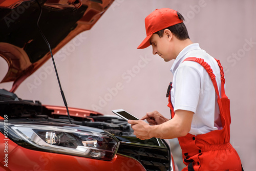 Car mechanic is using a tablet computer to check the car errors and problems and fix it. .