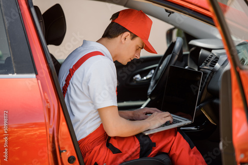 Car mechanic is using an laptop computer to check the car errors and problem and fix it. .