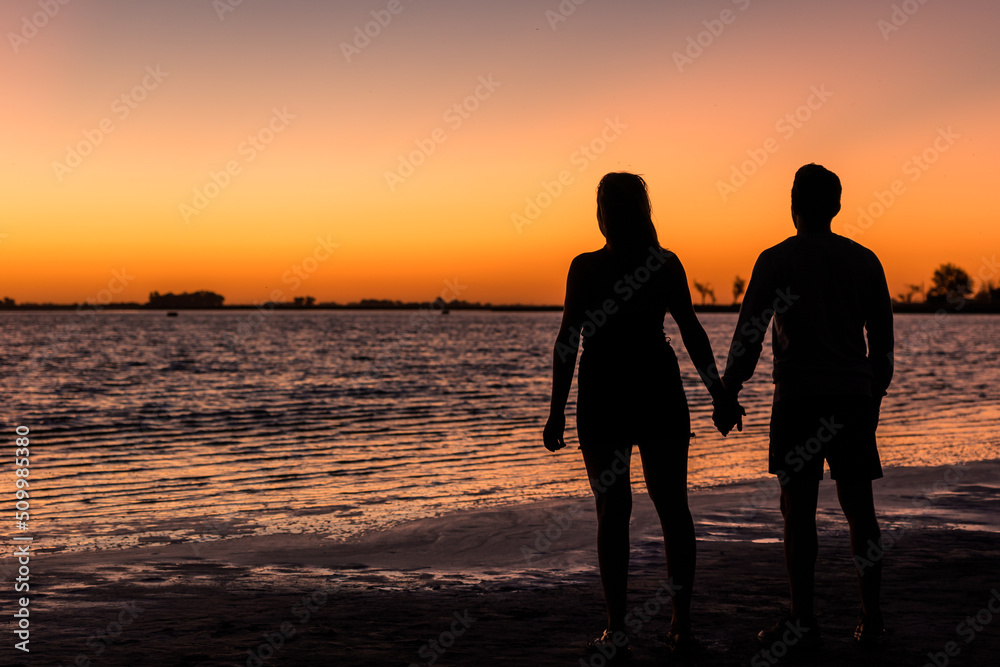 Young couple in love holding hands watching one of the best sunsets ever seen by the lake. Junin, Buenos Aires, Argentina