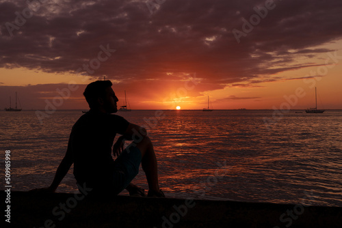 Silhouette of young man reflecting and contemplating nature by the beach during his relaxing and happy vacation