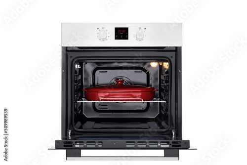 Electric oven with open door, illuminated and red baking dish. Front view. Isolated on white