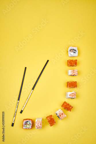 Ebi sushi rolls with red caviar near the chopsticks on the yellow background 