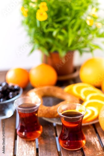 Turkish tea, sesame bagel, oranges and olives on wooden table