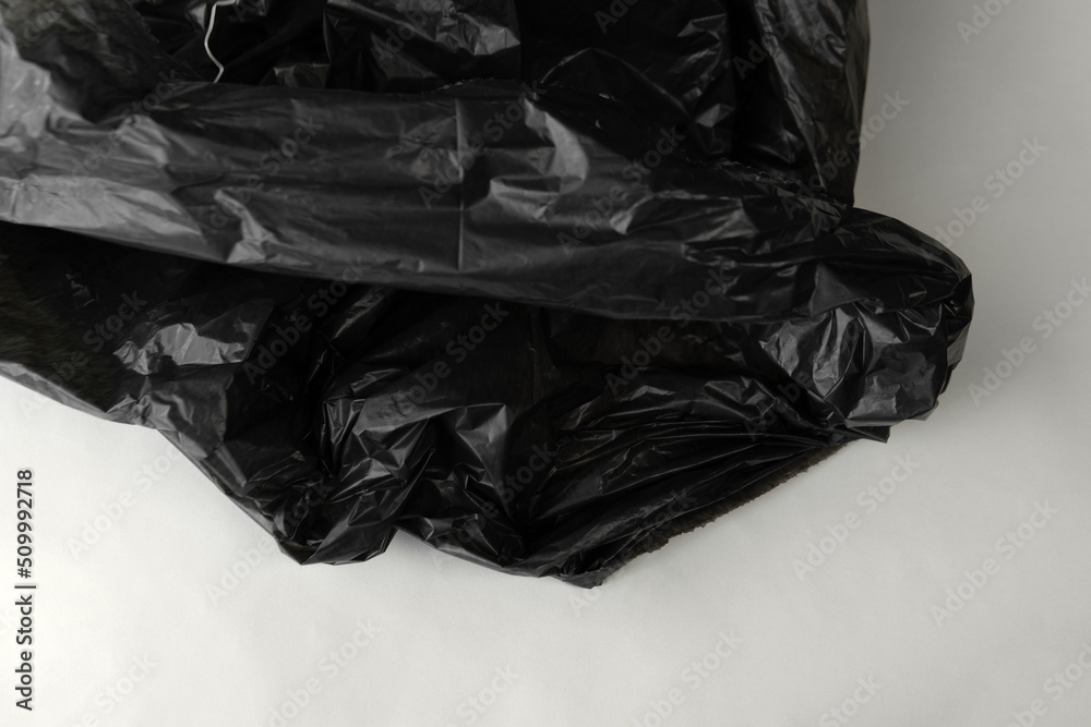 Closeup crumpled single use or non recyclable shiny black dark color plastic trash bag made from polyethylene texture white hygiene  isolated background. Environment care concept