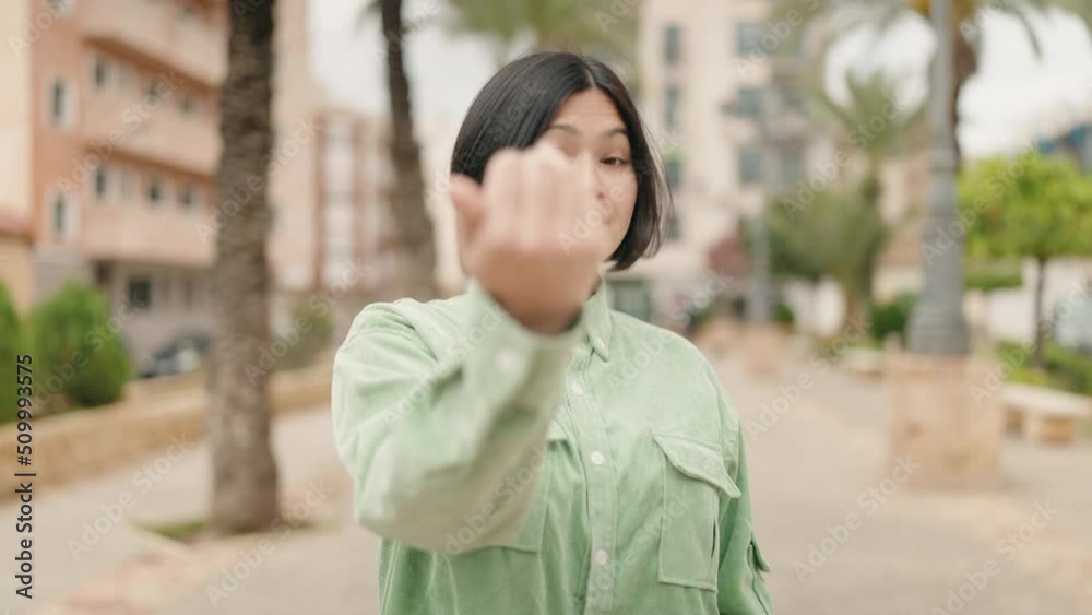 Young chinese woman smiling confident doing coming gesture with finger at park Young chinese woman smiling confident doing coming gesture with finger at park