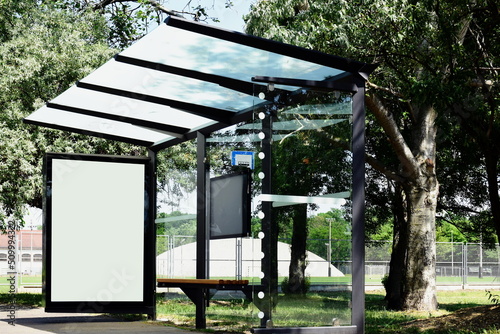 Fototapeta Naklejka Na Ścianę i Meble -  bus shelter at bus stop. blank white lightbox of glass and metal structure. street setting with green background. glass design. empty poster ad display. base for mockup. advertising concept