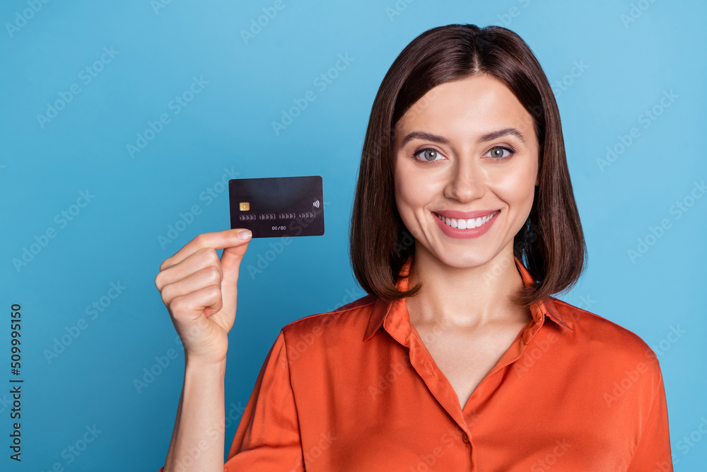 Portrait of attractive cheerful girl holding in hand bank card cashback service freelance isolated over bright blue color background Portrait of attractive cheerful girl holding in hand bank card cashback service freelance isolated over bright blue color background