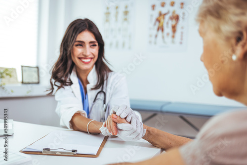 Shot of an doctor holding hands with her patient during a consultation.  Doctor holding hands of female patient at meeting as women health medical care concept.