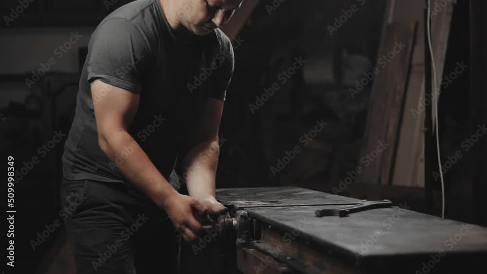 A worker prepares a woodworking machine for work in his home workshop. Making metal products with your own hands A worker prepares a woodworking machine for work in his home workshop. Making metal products with your own hands