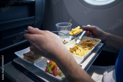 Obraz na plátně Passenger eating airline meal with metal cutlery