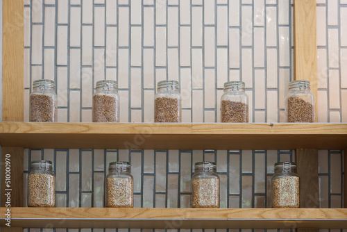 different roast coffee in glass jars on wooden shelf.