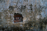 A close up shot of a damaged concrete wall with bricks exposed. India