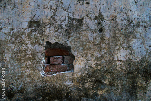 A close up shot of a damaged concrete wall with bricks exposed. India