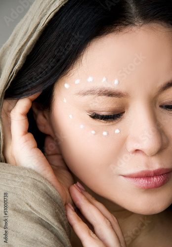 Portrait of of beautiful Asian woman with cream around the eye photo