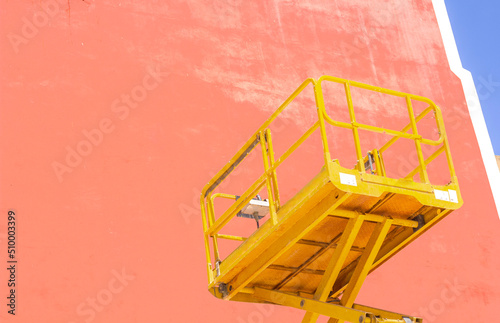 construction hoist of yellow color on the background of a pink wall