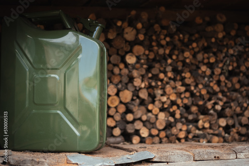 Green Jerrycan against wooden logs background. Gas canister full of gasoline. Fuel shortage while travelling far photo