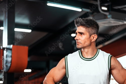 Close up portrait of healthy mature man standing at the gym and looking away. Confident mature man ready of workout..