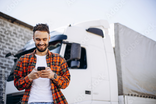Man trucker talking on the phone by his white truck photo