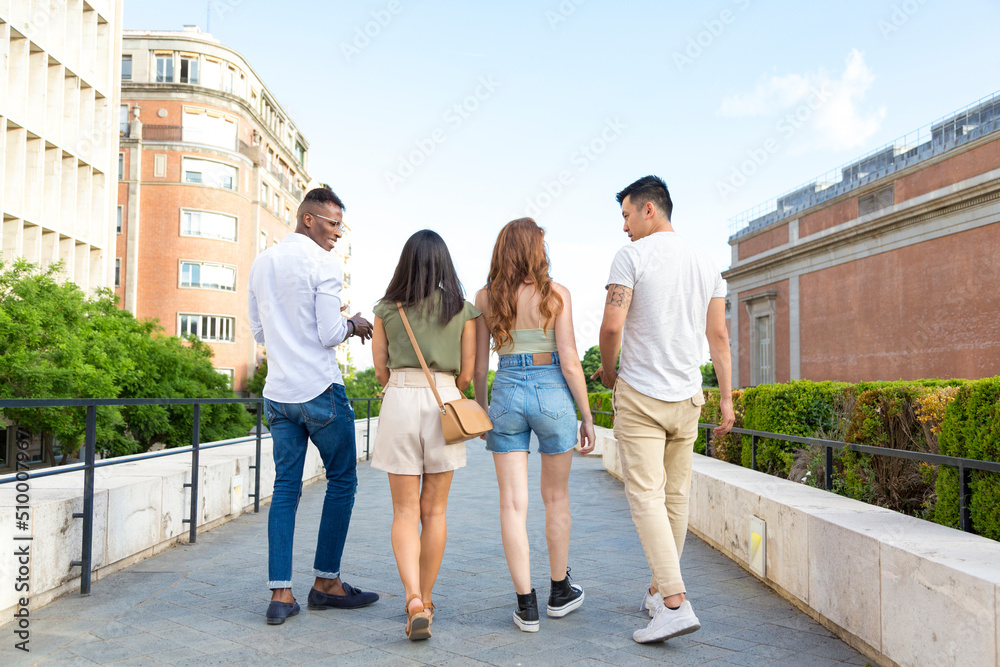 four unrecognizable multiracial young friends walking outdoor