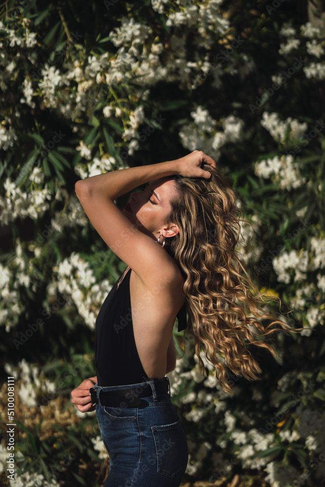 Chica delgada con pelo largo ondulado posando delante de flores Chica delgada con pelo largo ondulado posando delante de flores
