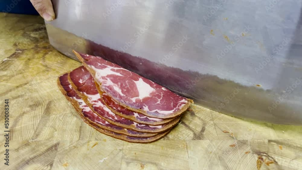 Cutting Pastirma slices from dried meat with chopping knife at Turkish