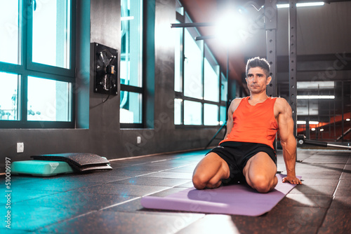 Portrait of mature active sporty man practicing yoga in gym. rabbit yoga pose. Healthy active lifestyle, working out indoors in gym..