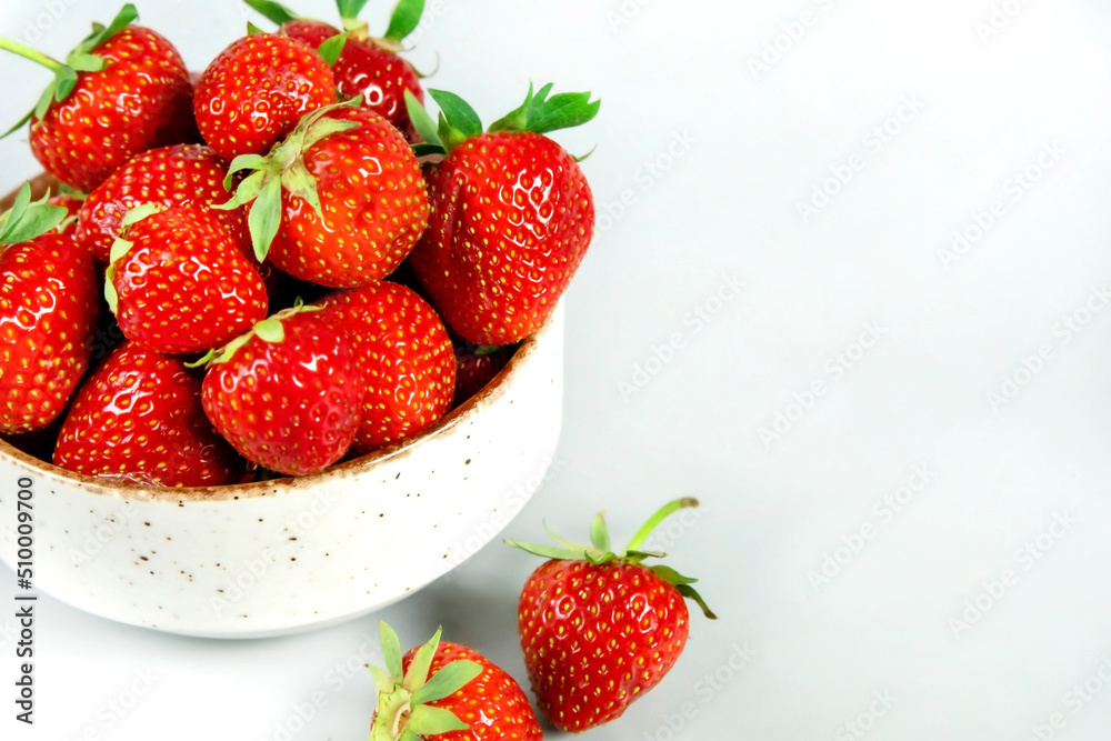 Fresh ripe tasty strawberries in a white bowl on a light background Fresh ripe tasty strawberries in a white bowl on a light background